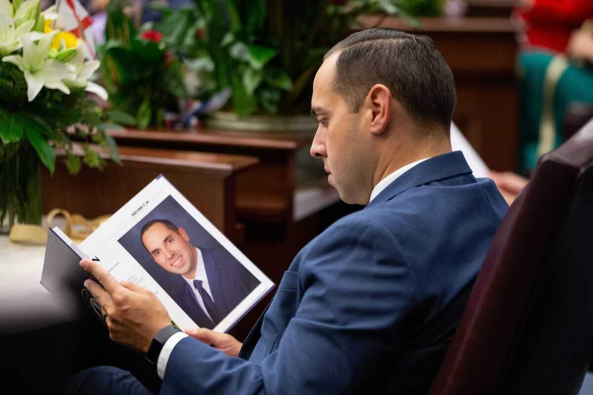 Sen. Bryan Avila flips through a book and stops to read a page featuring him and Miami-Dade during opening day of the 2023 Florida Legislative Session, Tuesday, March 7, 2023.