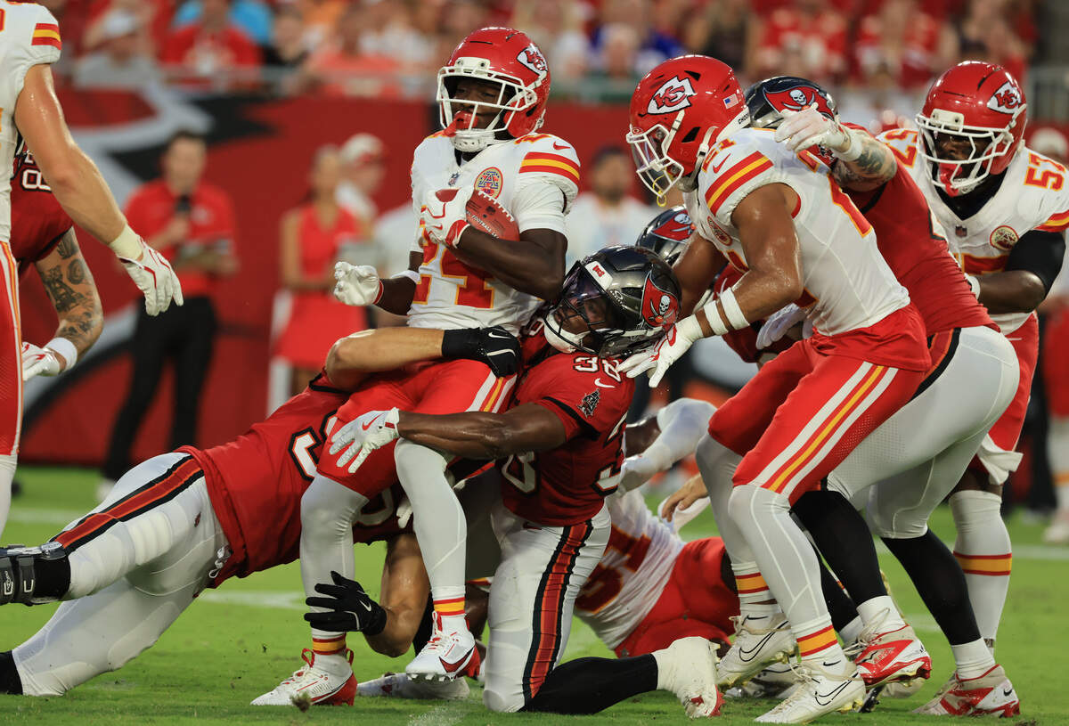 Tampa Bay Buccaneers linebacker Anthony Nelson (98) and safety Rashad Wisdom (38) tackle Kansas City Chiefs running back Brashard Smith (24) during a preseason NFL game at Raymond James Stadium in Tampa on Saturday, Aug. 22, 2026.
