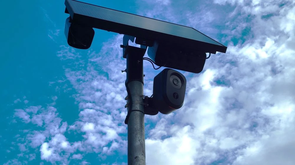 A Flock camera with a solar panel on top.