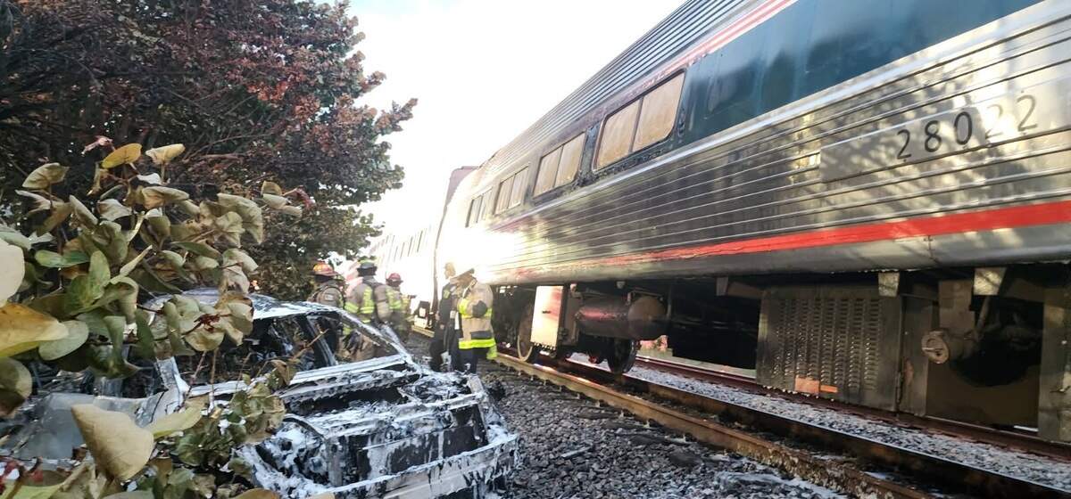 Firefighters battle a blaze near the Amtrak rail line in Broward at Northwest Ninth Avenue and West Prospect Road after a crash; officials continue investigating.