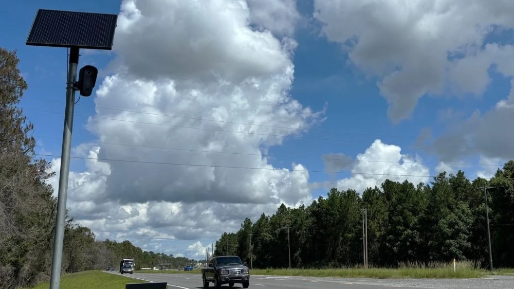 A Flock camera is shown along a road in Putnam County, with traffic passing by.