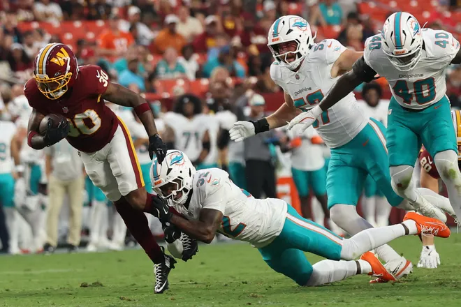 Aug 14, 2026; Landover, Maryland, USA; Washington Commanders running back Robert Henry Jr. (30) carries the ball as Miami Dolphins safety Lonnie Johnson Jr. (32) makes the tackle during the first half at Northwest Stadium. Mandatory Credit: Geoff Burke-Imagn Images