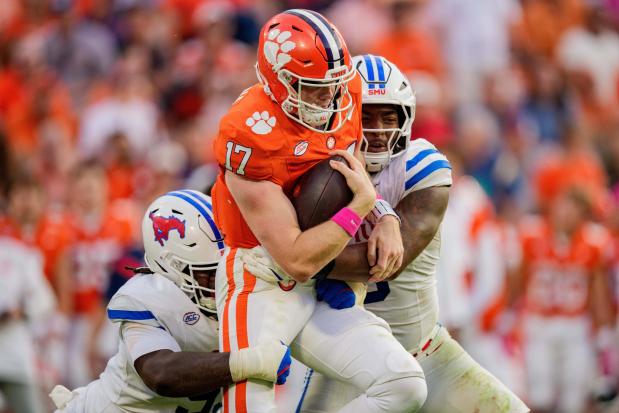 FILE - SMU defensive lineman Kevin Allen, left, and defensive end Cameron Robertson, right, tackle Clemson quarterback Christopher Vizzina (17) in the second half of an NCAA college football game, Oct. 18, 2025, in Clemson, S.C. (AP Photo/Jacob Kupferman, File)