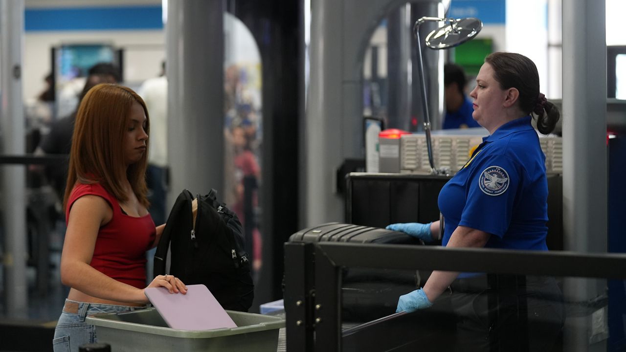 A traveler puts her laptop in a tray before going through a TSA security checkpoint. (AP Photo/Damian Dovarganes)