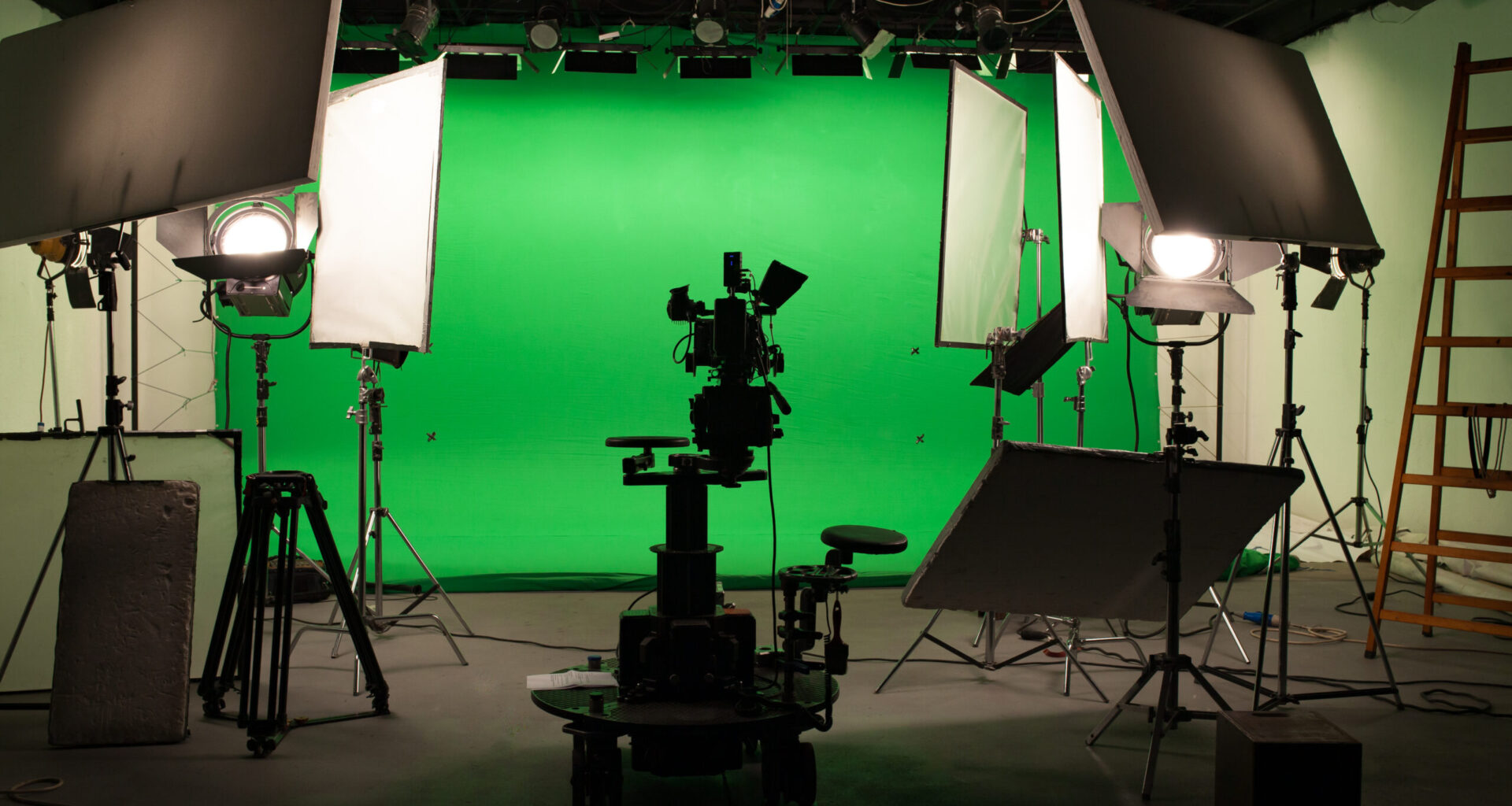 Television production studio with camera, lighting equipment and a green screen.