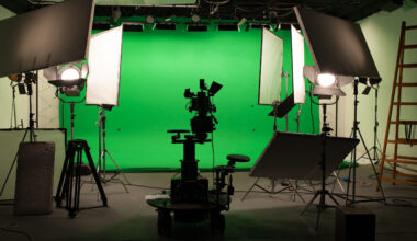 Television production studio with camera, lighting equipment and a green screen.