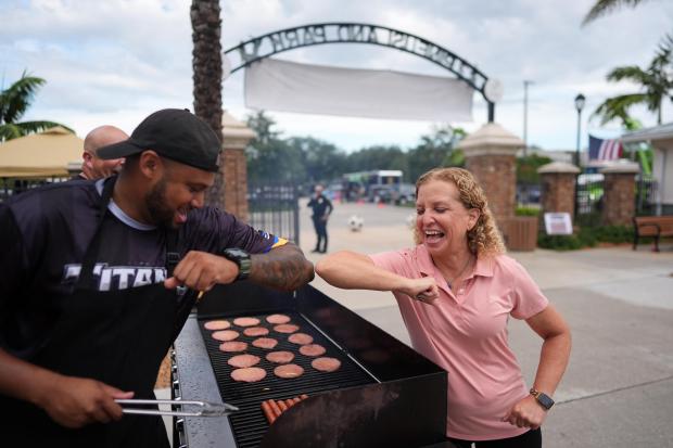 U.S. Rep. Debbie Wasserman Schultz greets a man tending to a grill as she visits a community event in Plantation on Aug. 4, 2026. (Rebecca Blackwell/Associated Press).