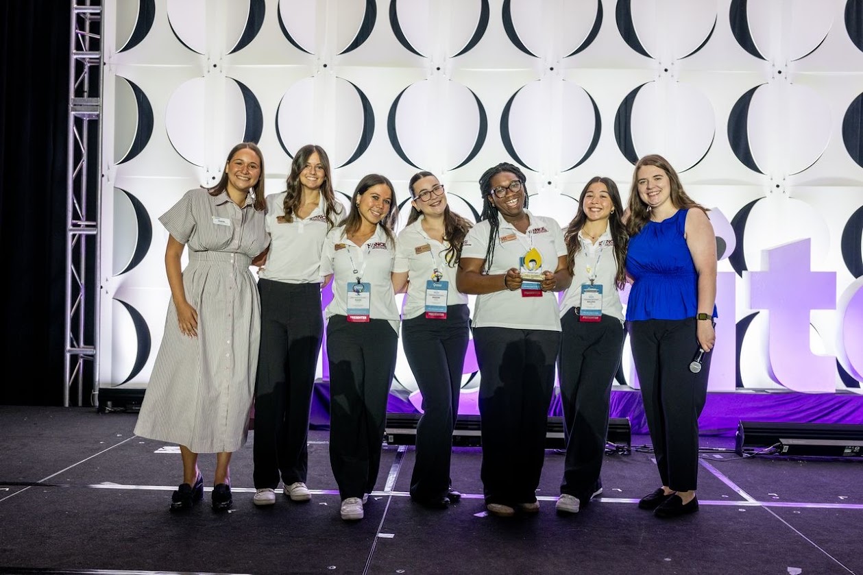 Dance Marathon at FSU members smile on a stage holding an award.