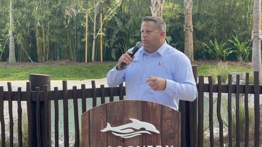 Brad Gilmour speaking at a podium at Discovery Cove for 25th anniversary.
