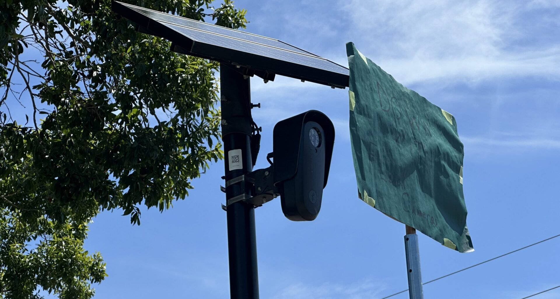 A sign reading "Down with the Flock" blocks a Flock camera