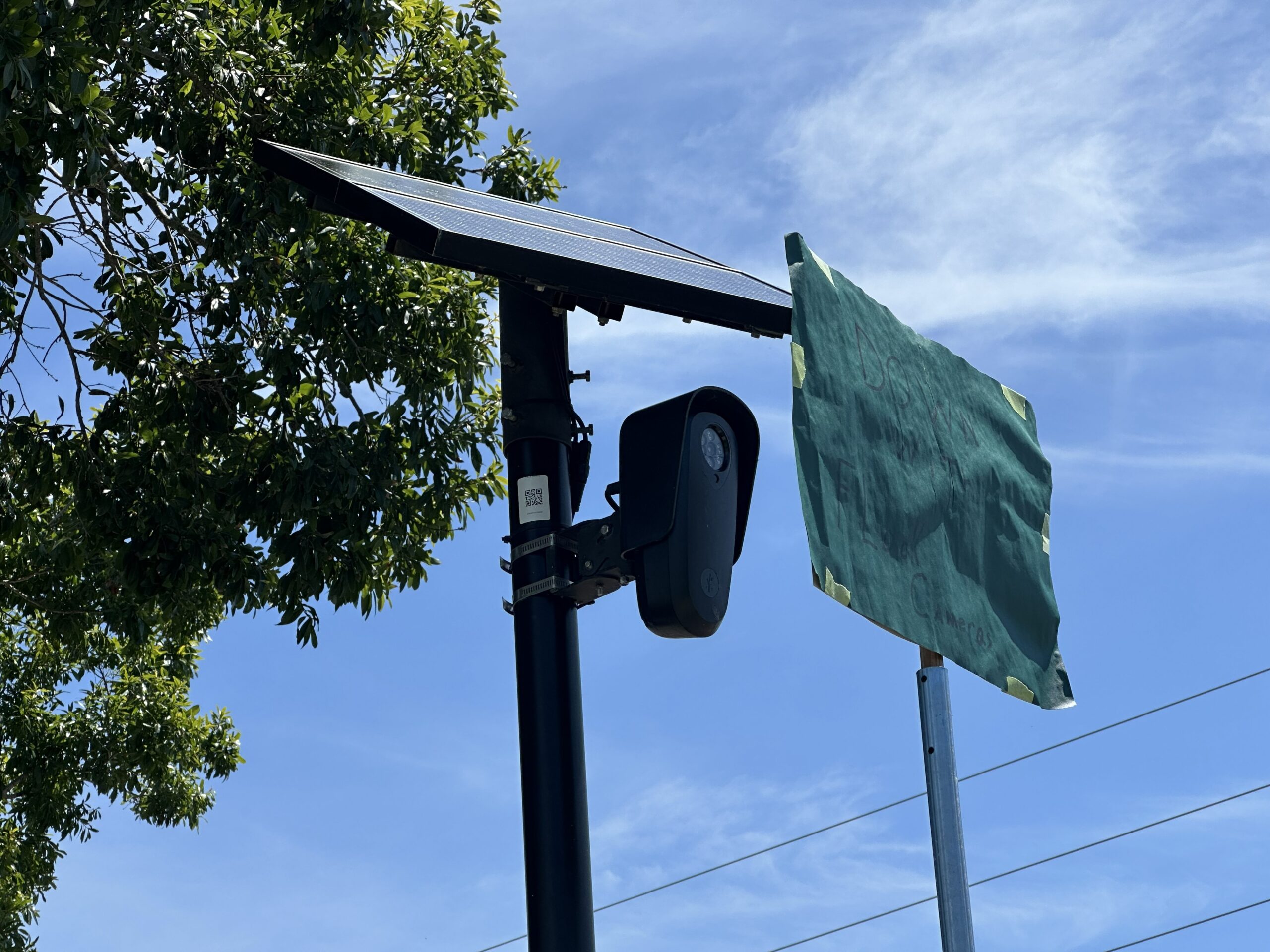 A sign reading "Down with the Flock" blocks a Flock camera