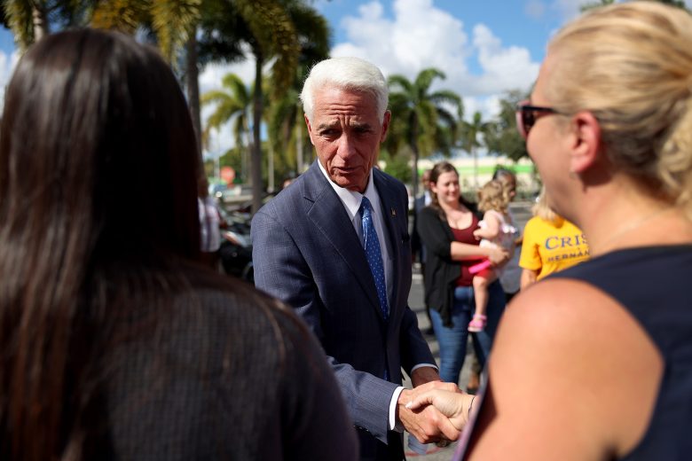 Charlie Crist shakes hands with a supporter at an outdoor event in Fort Lauderdale.
