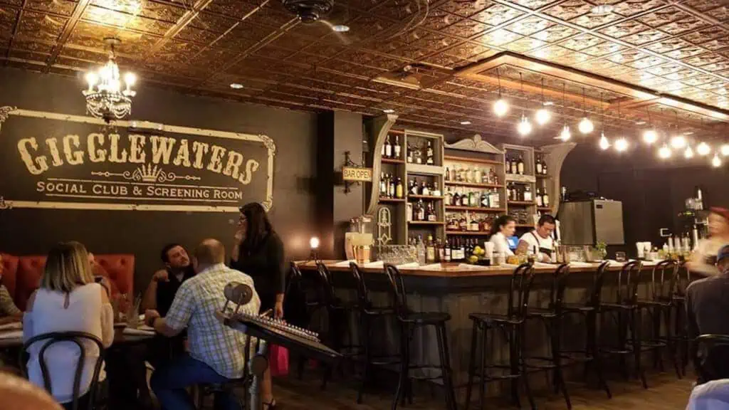 interior of a bar and restaurant with a Gigglewaters sign above the bar