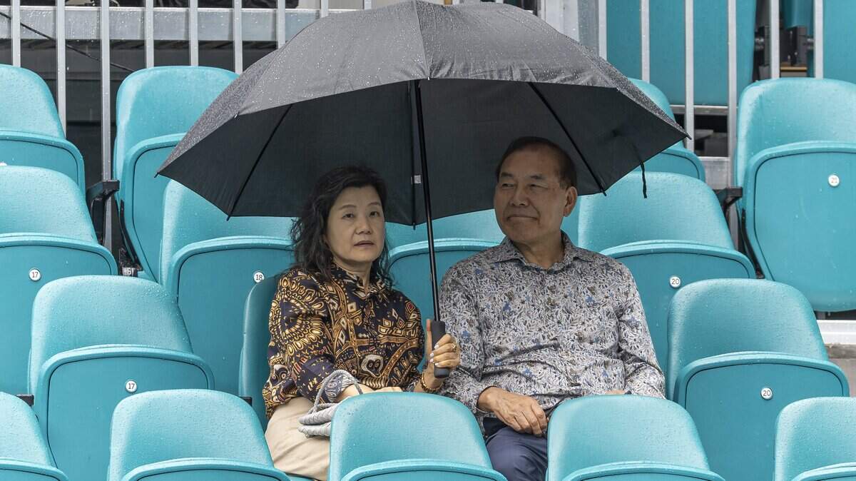 Fans use an umbrella as a rain delay is issued before the start of the men's final singles match between Jiri Lehecka of Czechia and Jannik Sinner of Italy at the Miami Open tennis tournament on Sunday, March 29, 2026, in Miami Gardens, Fla.
