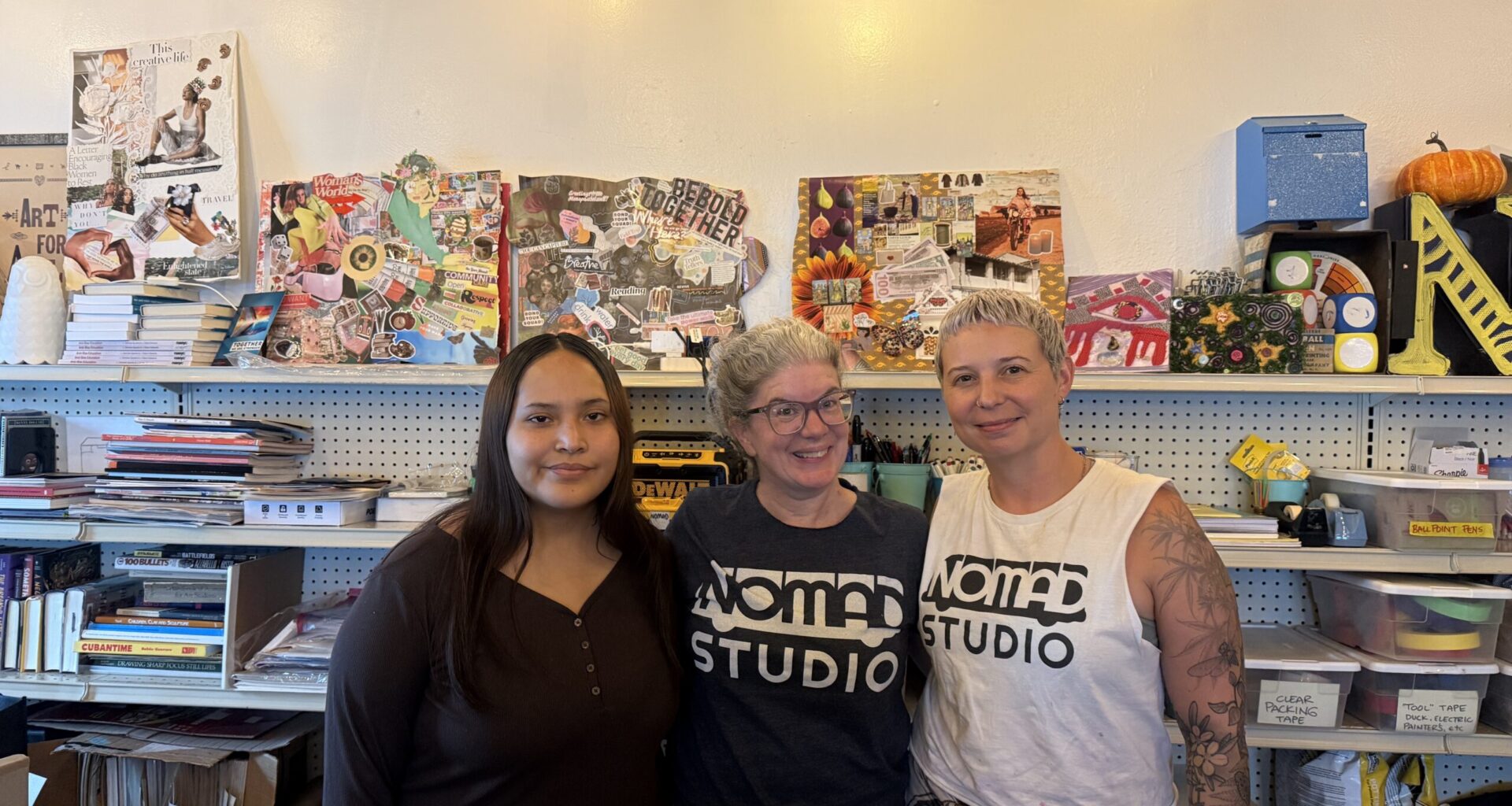 Misha (left), Carrie Boucher (Center), Kinsey Rodriguez (left) in front of collages and artwork in the St Pete office of NOMADstudio. August 11, 2026. Photo by Juanita Hurtado Huerfano/ WMNF news.