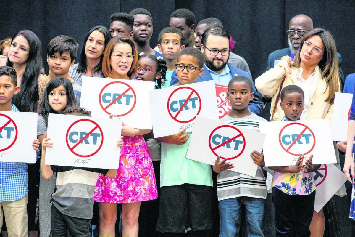 Schoolchildren holding signs against the concept of critical race theory stand on stage alongside Florida Gov. Ron DeSantis as he addresses the crowd before signing HB 7, titled the 'Individual Freedom' bill but also dubbed the "Stop Woke Act," during a press conference at Mater Academy Charter Middle/High School in Hialeah Gardens, Florida, on Friday, April 22, 2022.