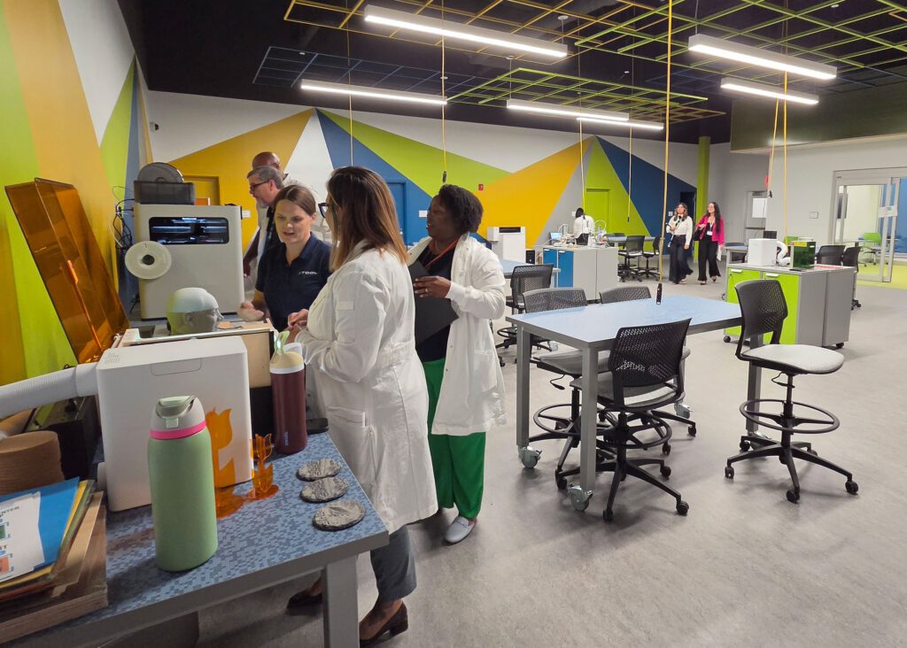 Several people standing next to equipment in a lab space.