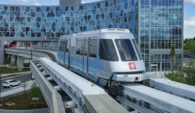 A Skyway train moving on a monorail, with the JTA headquarters in the background.
