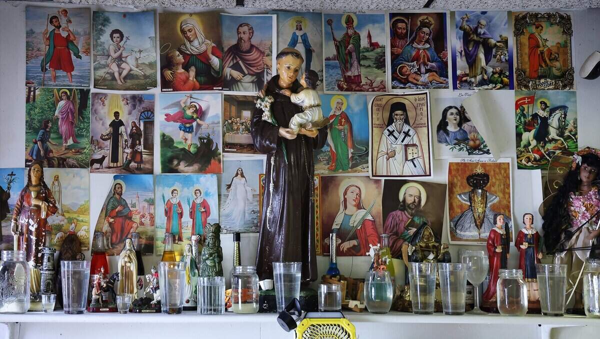 The altar, Mesa Blanca, at the entrance of Botanica Santo Tomas in Fort Lauderdale holds figurines and images of saints, offerings, glasses of water left by practitioners as expressions of faith, and other religious items, Monday, July 20, 2026.