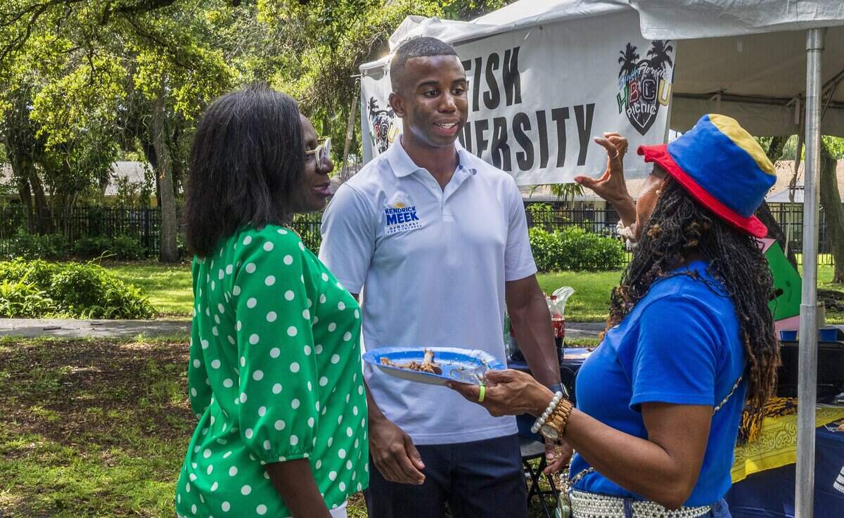 Kendrick Meek talks with Representative Felicia Robinson (left) and Carlota Sullivan, at the tent of the Fisk University, as he rallies during the South Florida HBCU Picnic, to follow in his family's legacy and get elected to Congress, at the Rolling Oaks Park in Miami Gardens, on Saturday July 25, 2026.