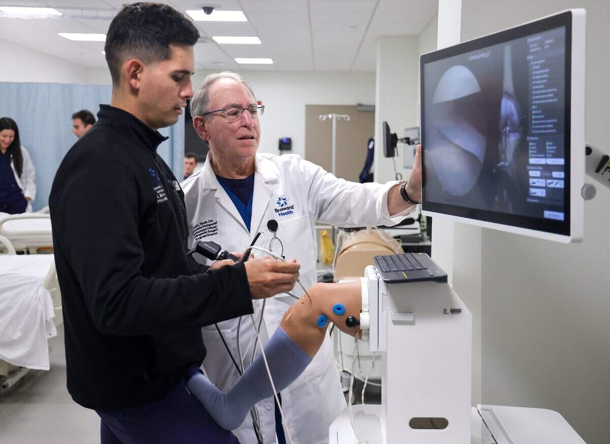 Inside the GME Education Center at Broward Health Medical Center, resident Dr. Alex Blanca, left, and program director Dr. Joel Rush, right, operate the high-tech Orthopedic arthroscopy simulator on Thursday, July 23, 2026.