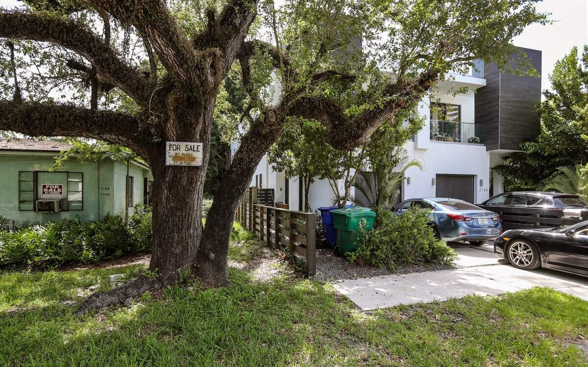 A new "sugar cube" duplex home, right, loomed over a 1947 rental duplex for sale on Elizabeth Street in Miami’s historically Black West Coconut Grove in 2022. The mostly low-income Black community is being rapidly displaced as new multi-millionaire homes, most purchased by white owners, proliferate in the neighborhood.