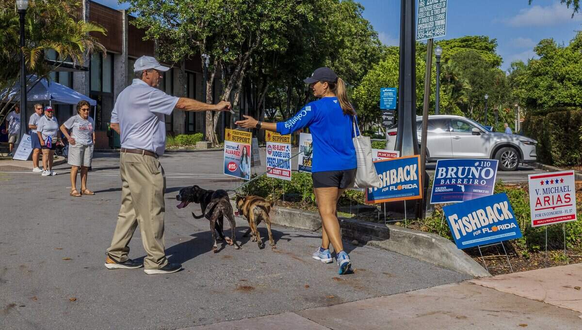 Candidate for U.S. Congress V. Michael Arias hands out a flyer to a resident out side of the Coral Gables Branch Library poll site, during the last weekend of early voting, looking ahead to Tuesday's election, on Saturday August 15, 2026.