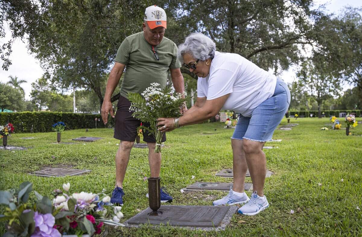 Raunel Sanchez and Vivian Texidor, the parents of the late Raudel Sanchez, place flowers at their son's gravesite at Caballero Rivero Woodlawn West on Sunday, Aug. 9, 2026, in Miami, Fla. Raudel, 21, was murdered on Aug. 27, 2009. His death remains a cold case, and no one has been arrested in connection with the crime.