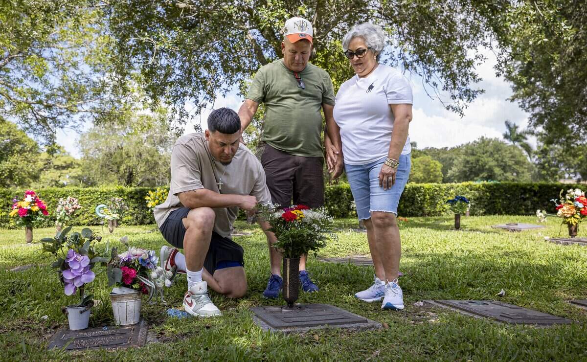 From left to right: Miguel Esteris, cousin of the late Raudel Sanchez, Raunel Sanchez, his father, and Vivian Texidor, his mother, pay their respects at Raudel's gravesite at Caballero Rivero Woodlawn West on Sunday, Aug. 9, 2026, in Miami, Fla. Raudel, 21, was murdered on Aug. 27, 2009. His death remains a cold case, and no one has been arrested in connection with the crime.