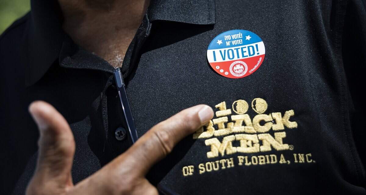 Phil Roundtree, a member of 100 Black Men of South Florida, points to the sticker he received after early voting at the North Dade Regional Library on Saturday, Aug. 15, 2026, in Miami Gardens, Fla.