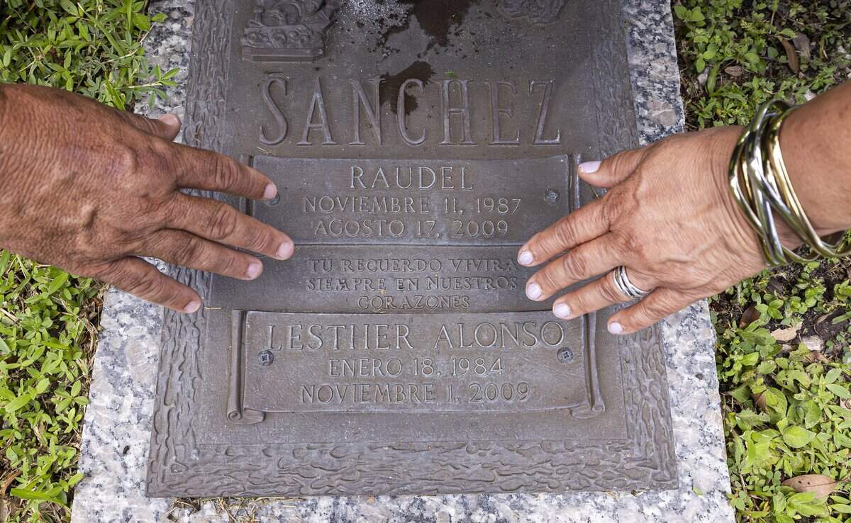 Raunel Sanchez and Vivian Texidor, the parents of the late Raudel Sanchez, touch their son’s grave marker at Caballero Rivero Woodlawn West on Sunday, Aug. 9, 2026, in Miami, Fla. Raudel, 21, was murdered on Aug. 27, 2009. His death remains a cold case, and no one has been arrested in connection with the crime.