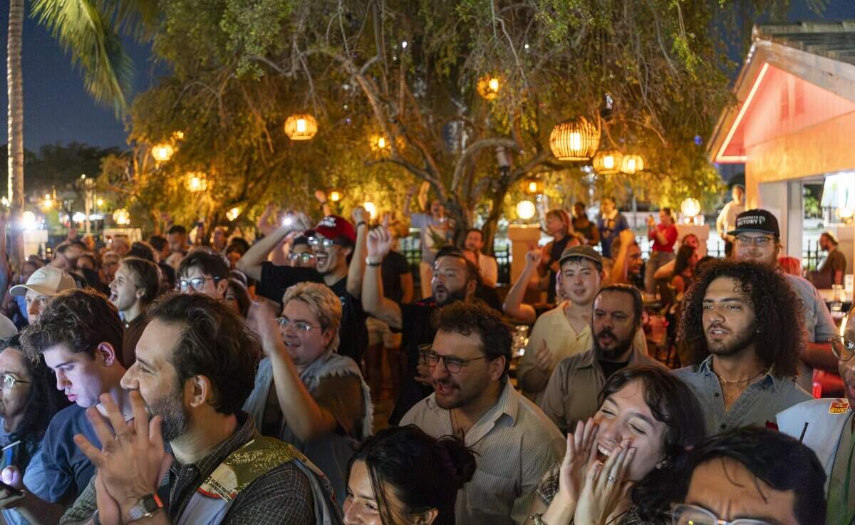 Attendees cheer as Oliver Larkin, who is running for the U.S. House of Representative District 25, speaks during the Chomp The Oligarchy rally at Sidewalk Bottleshop on Friday, Aug. 14, 2026, in Fort Lauderdale, Fla. The political rally aimed to promote democratic socialist candidates but was forced to relocate twice in 24 hours after two Fort Lauderdale venues pulled out following backlash.