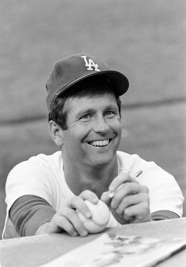 FILE - Lefthander Tommy John of the Los Angeles Dodgers signs an autograph before a game, Aug. 12, 1977. (AP Photo/Lennox McLendon, File)