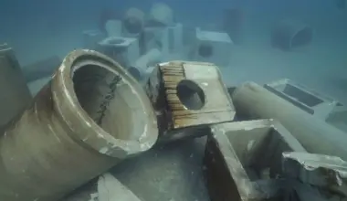 Concrete culverts and piping lay on the ocean floor, forming an artificial reef.