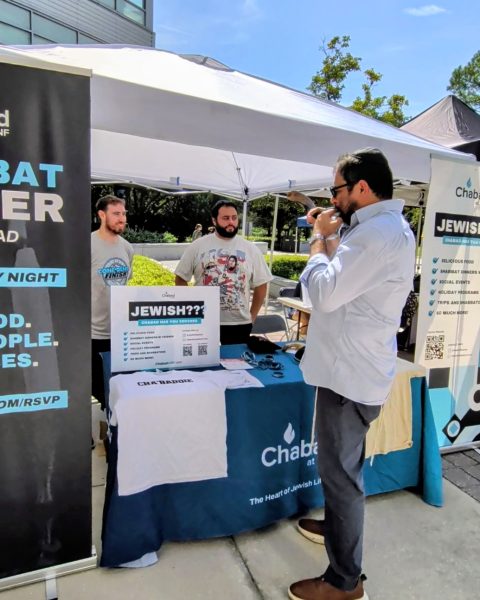 Rabbi Novack blowing the shofar at a table for the Jewish center at UNF