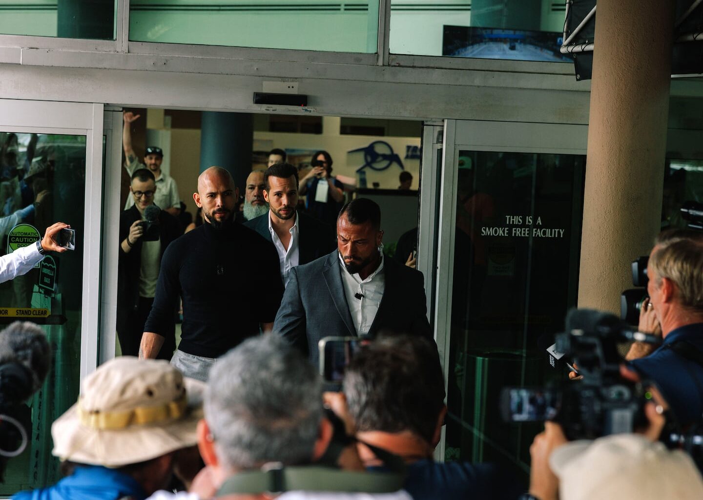 Andrew Tate, left in black, and his brother Tristan Tate, center rear, arrive at Fort Lauderdale-Hollywood International Airport in Florida on Feb. 27, 2025.