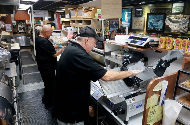Victor Rodriguez and Paul Wagner slice up pastrami at Pomperdale's Famous New York Deli in Fort Lauderdale on Friday, August 7, 2026. August is National Deli Month, and several local delis are participating. One is Pomperdale's, where customers can, for every order of a Super Stuffed New Yorker sandwich, the buyer will get a free bottle of New York Deli Mustard, a beer for just $1 and 10% off the entire order. (Mike Stocker/South Florida Sun Sentinel)