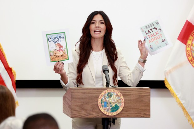 Orange County School Board Member Alicia Farrant holds up the cover of a book 'Charlotte's Web' and the book 'Let's Talk About It' during a news conference held by Florida Gov. Ron DeSantis at UCF Lake Nona Cancer Center in Orlando on Thursday, Feb. 15, 2024. Farrant, who was a member of the conservative Moms for Liberty group, lost her election for the countywide school board chair last week to Angie Gallo. (Rich Pope, Orlando Sentinel)