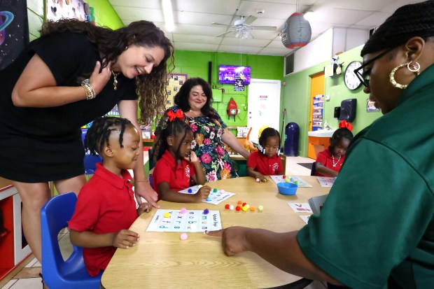 Jamie Dozier, left, with the REED Charitable Foundation, and teacher Latina Woodson, right, help pre-schooler Alexander Sweetland with an alphabet exercise at Nu Generation Academy in Orlando, Monday, August 10, 2026. REED Charitable a literacy and education training non-profit was a primary beneficiary of Visit Orlando's Magical Dining event in 2025. The annual dining program showcases more than 160 restaurants featuring prix-fixe menus with a portion of proceeds going to local charities. (Joe Burbank/Orlando Sentinel)