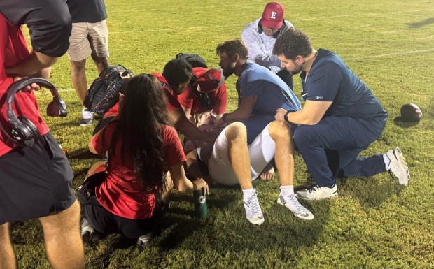 Doctors (right) and team trainers (in red) attend to Edgewater quarterback Joe Aicher after he was injured during Friday night's Kickoff Classic game against Armwood. Edgewater coach Patrick Browning (red hat) looks on. The game was called after the injury, ending in a 14-14 tie. (Chris Hays/Orlando Sentinel)