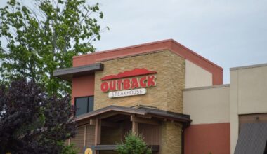 Exterior of an Outback Steakhouse restaurant with the chain’s red logo above the entrance.