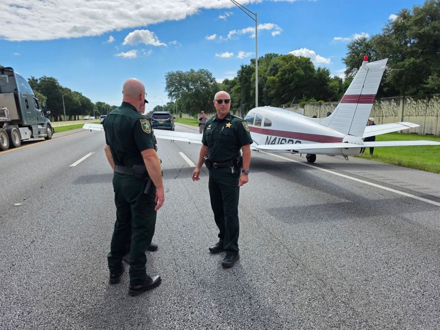 A small plane sits on the side of Interstate 10 in Pensacola, Florida after making an emergency landing on the highway, Monday.