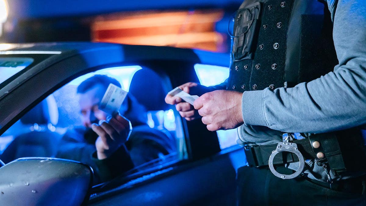 Police officer checks the identity of a stopped driver at night.