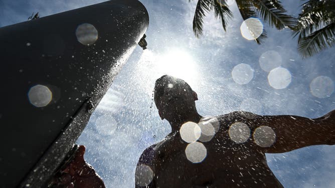 A man takes a shower in the middle of a hot afternoon in Miami Beach, Florida, on July 22, 2025. Some 85 million Americans from South Dakota to Texas and North Carolina to Florida are under National Weather Service extreme heat warnings, watches or advisories, with temperatures reaching 100 degrees Fahrenheit (38 degrees Celsius). (