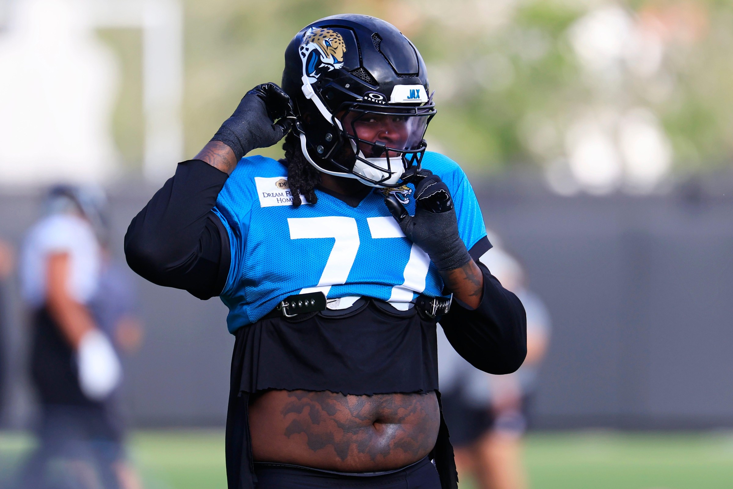 Jacksonville Jaguars offensive tackle Anton Harrison (77) straps on his helmet during the sixth day of NFL training camp at the Miller Electric Center on Tuesday, Aug. 4, 2026, in Jacksonville, Fla.