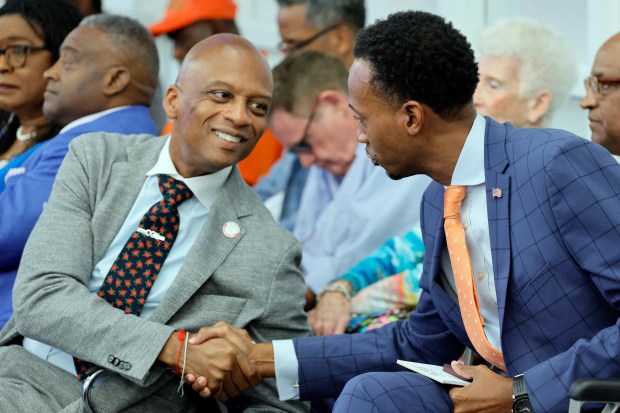 Torey Alston, right, reaches out to Miami-Dade County Commissioner Oliver Gilbert during a Broward College District Board of Trustees meeting at the College's Fort Lauderdale campus on Tuesday, Aug. 25, 2025. It was announced during the meeting that the College and Torey Alston had signed a mutual separation agreement. (Amy Beth Bennett/South Florida Sun Sentinel)