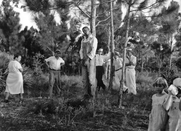 A group of people look at the dead body of 32-year old Rubin Stacy hanging from a branch of a pine tree, in Fort Lauderdale, Fla., USA, July 19, 1935. Stacy was forcefully kidnapped from the custody of the deputy by a masked mob resorting to lynch law. Stacy was accused of having attacked a white woman. (AP Photo/Str)