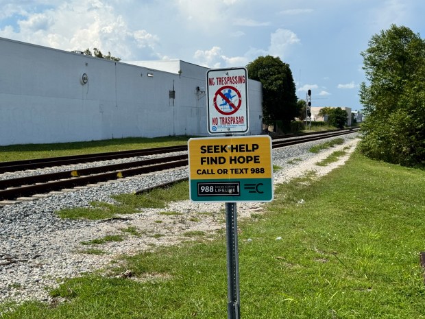A no trespassing sign and 988 suicide prevention sign by the Brightline train tracks in South Florida on Aug. 13, 2026. (Mary Anna Mancuso/Miami Herald)