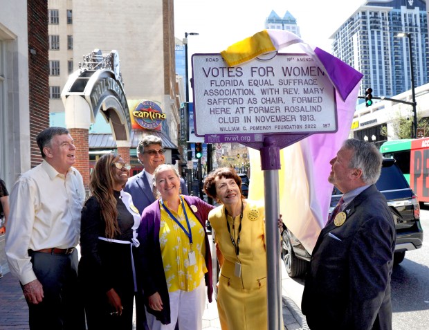 Orlando Mayor Buddy Dyer, right, unveils a historical marker on Orange Avenue recognizing Orlando's pivotal role in the early 20th-century national suffrage movement during a dedication ceremony in 2023. (Joe Burbank/Orlando Sentinel file)