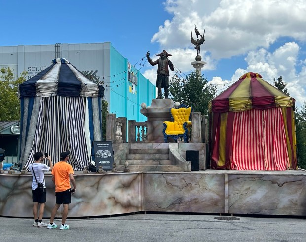 Universal Studios visitors check out a statue of Jack the Clown, frequently the face of the theme park's Halloween Horror Nights events. The figure is part of the preparation of a scare zone for the after-hours fright fest, which begins Aug. 28. (Dewayne Bevil/Orlando Sentinel)